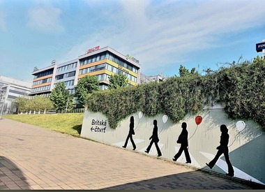 Foto 5 Mural v pěší trase administrativního komplexu. Velkoformátový mural oživuje pěší trasu a posiluje vizuální orientaci v území. Jasné grafické prvky zvyšují čitelnost prostoru a podporují přirozený dohled v exponované části areálu.