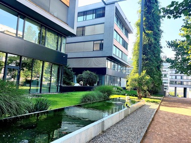 Foto 1 Relaxační zóna administrativního komplexu. Vodní zrcadlo a udržovaná zeleň vytvářejí klidový prostor v zadní části areálu. Otevřené průhledy a kvalitní pobytové prvky podporují přehlednost a bezpečné využívání místa.
